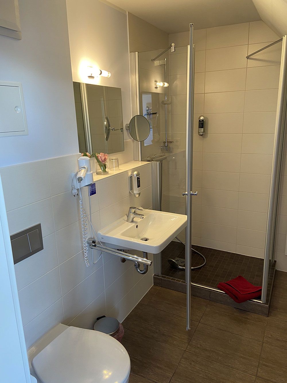 Ein Badezimmer mit Toilette, Waschbecken, Spiegel und Dusche.