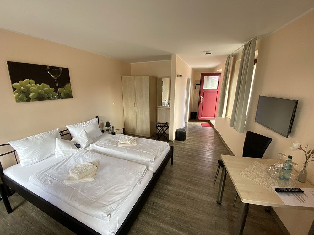 Ein Hotelzimmer mit zwei Betten, einem Tisch und einem Fernseher.