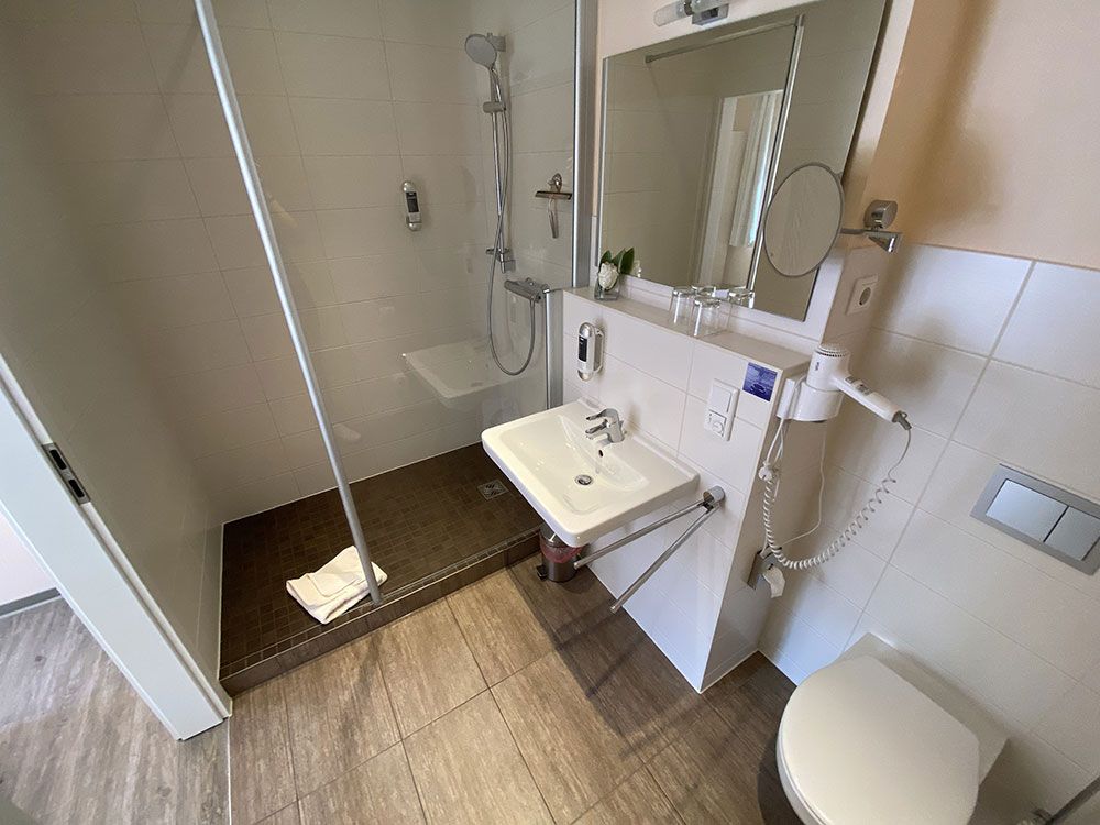 Ein Badezimmer mit Waschbecken, Toilette, Dusche und Spiegel.