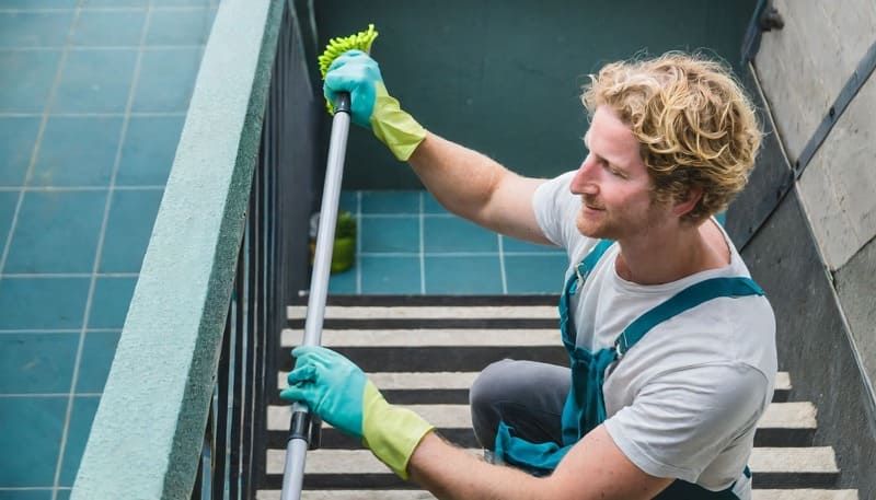 Ein Mann reinigt die Treppe mit einem Mopp | MMJ Glas- und Gebäudereinigung