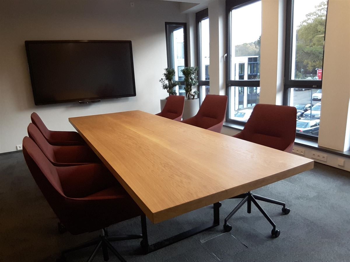 Ein Konferenzraum mit einem langen Holztisch und roten Stühlen
