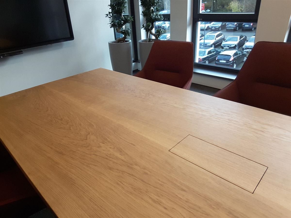 Ein Konferenzraum mit einem Holztisch und roten Stühlen