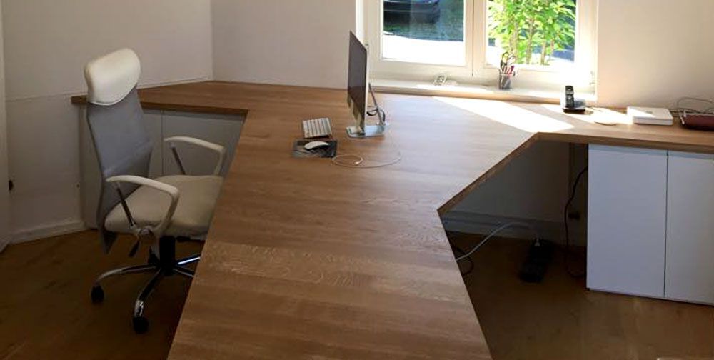 Ein Holzschreibtisch mit einem Stuhl und einem Computer darauf.