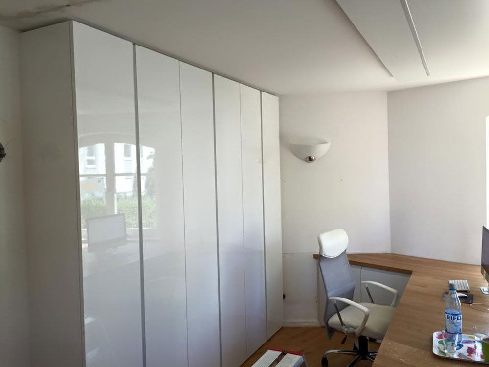 Ein Zimmer mit weißen Schränken und einem Schreibtisch mit Stuhl