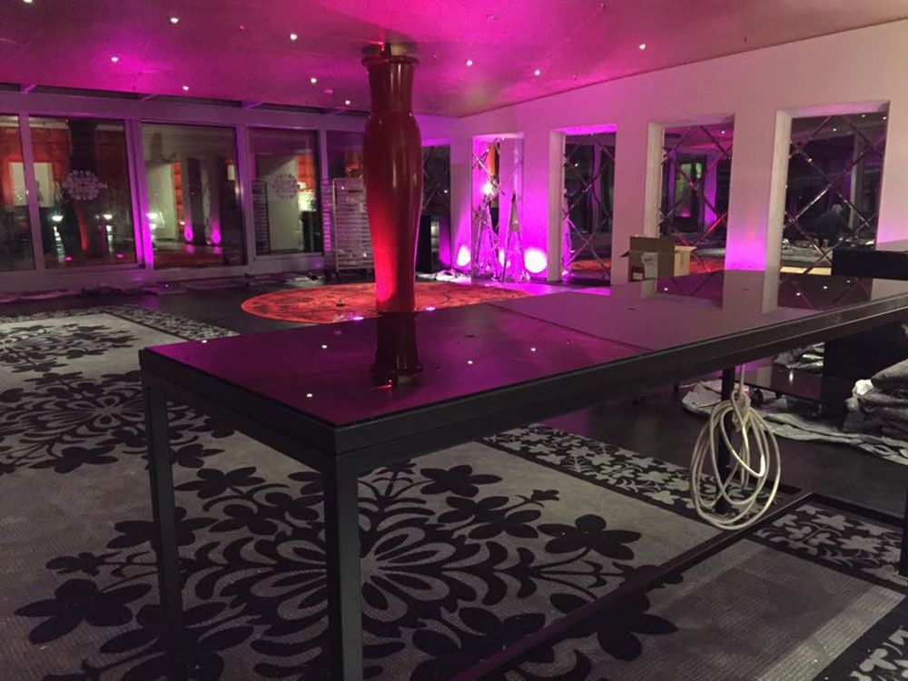 Ein Tisch mit einer Vase darauf in einem Raum mit violettem Licht