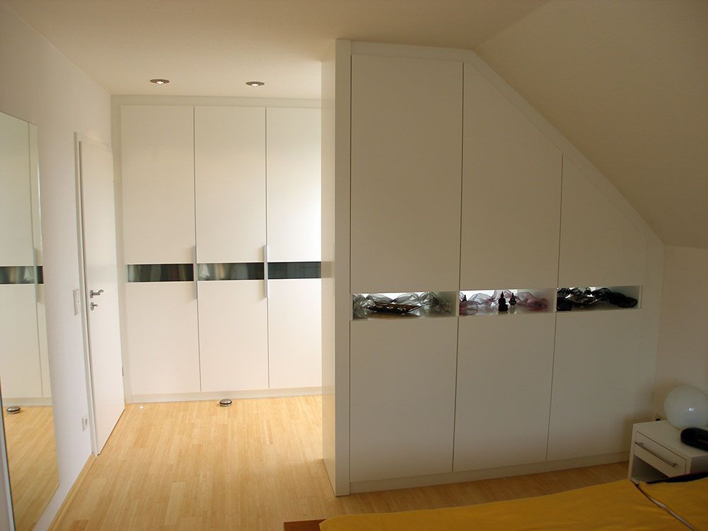 Ein Schlafzimmer mit Dachschräge und weißen Schränken