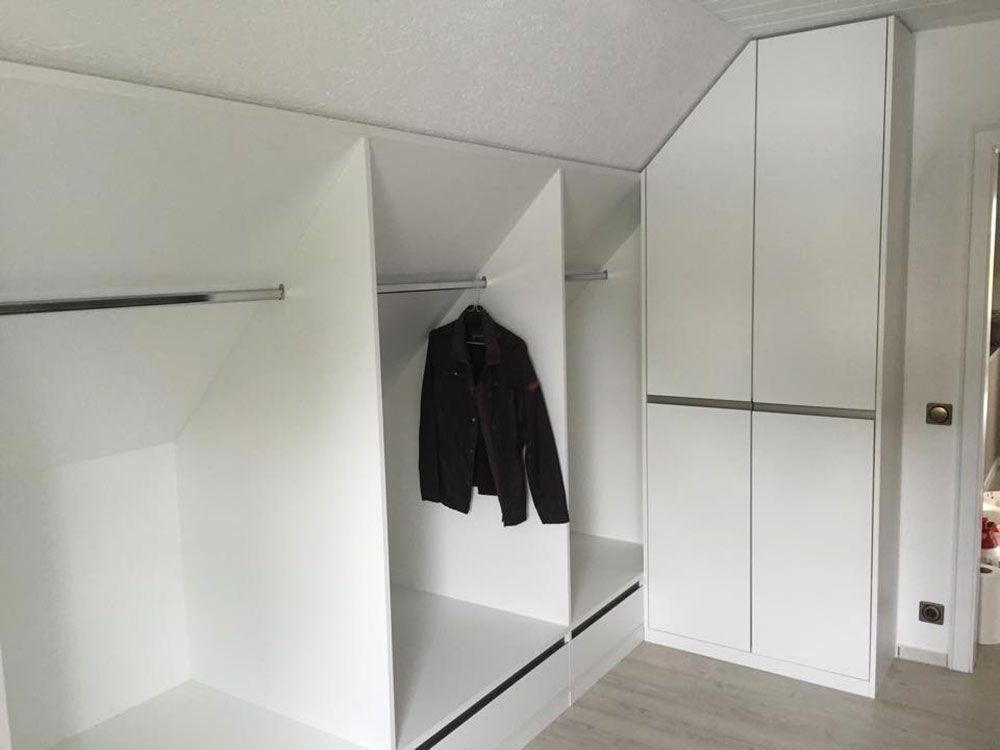Eine schwarze Jacke hängt in einem weißen Schrank.
