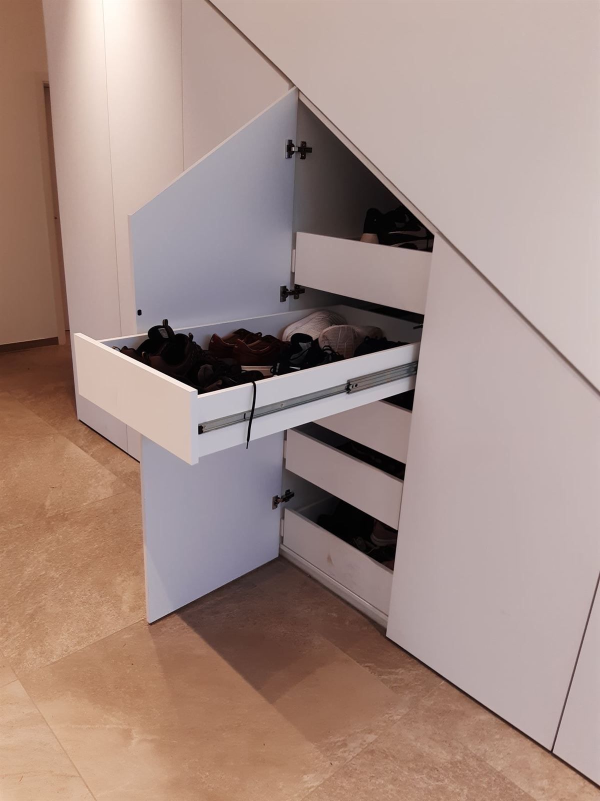 Eine Schublade unter einer Treppe voller Schuhe