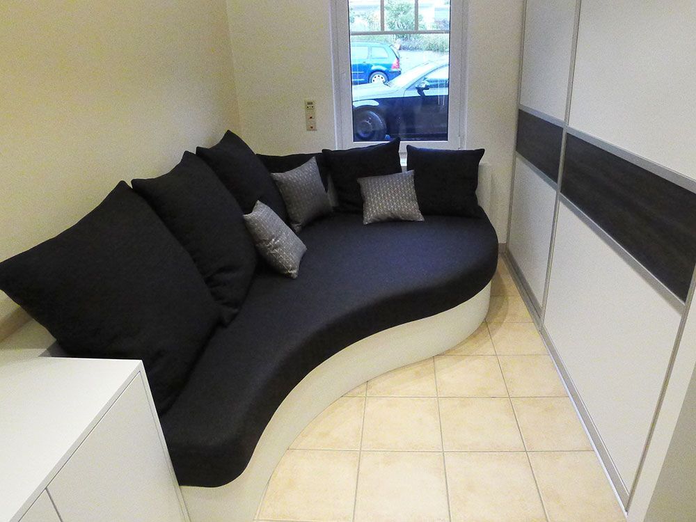 Eine geschwungene Couch mit schwarzen und weißen Kissen in einem Zimmer