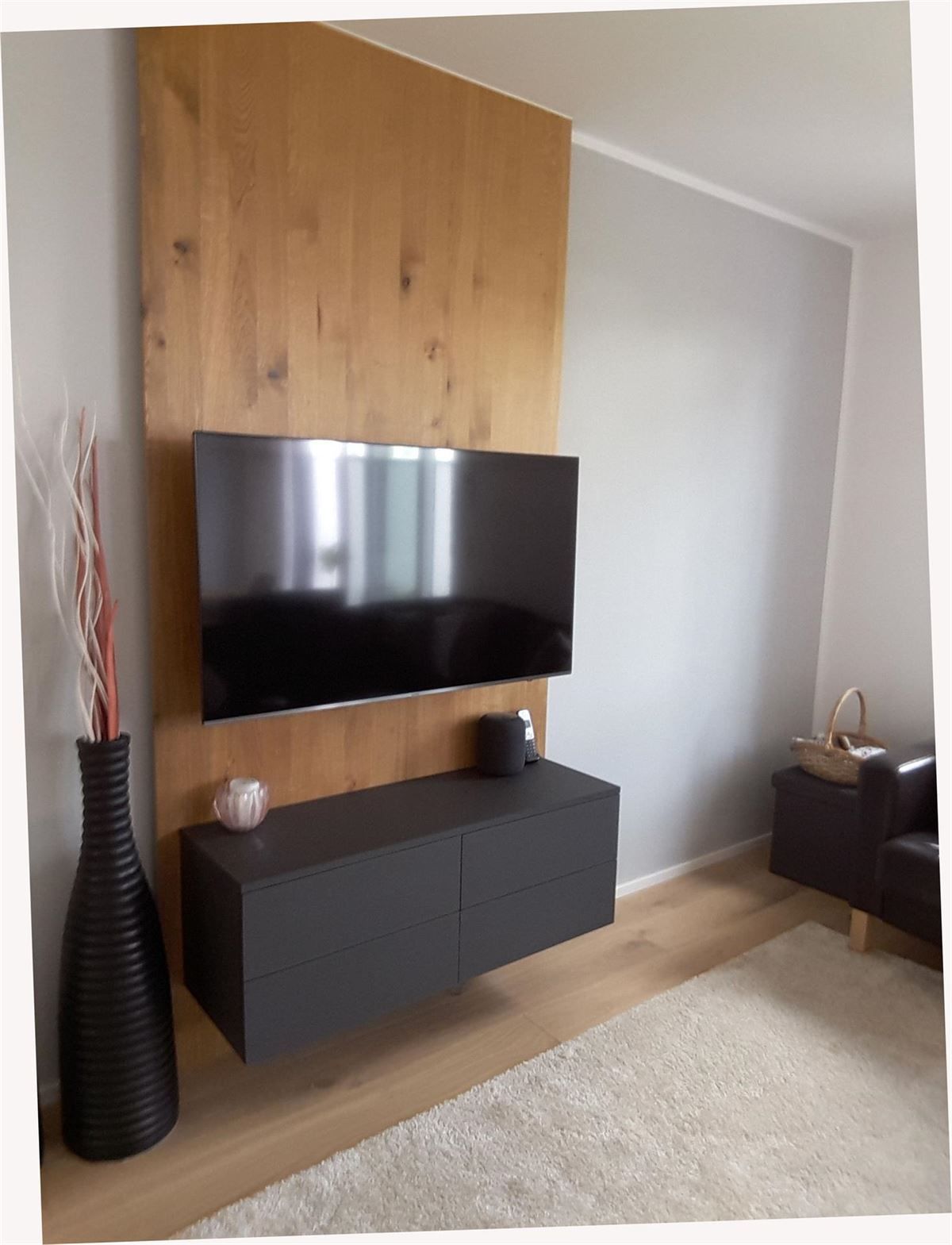 Ein Wohnzimmer mit einem an der Wand montierten Flachbildfernseher