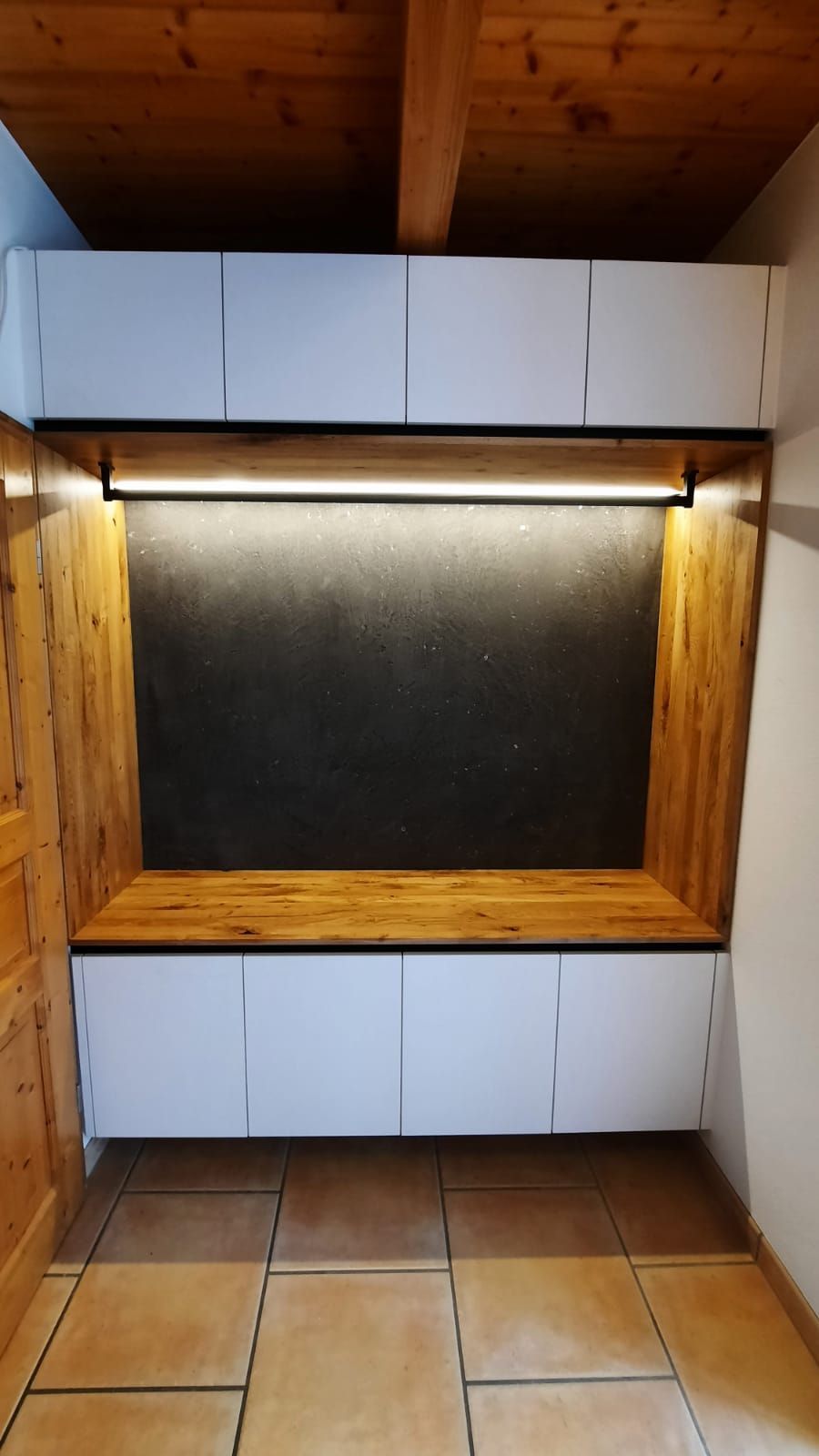 Ein Raum mit einer Holzbank und weißen Schränken.