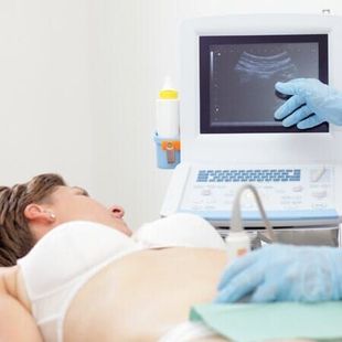 Paciente grávida fazendo exame de ultrassom enquanto o médico aponta para o monitor.