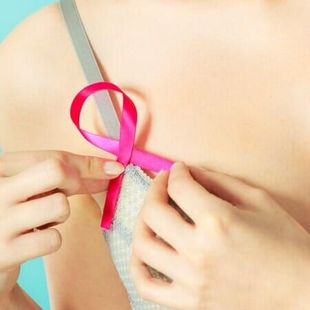 Mãos amarrando uma fita rosa brilhante em uma pequena caixa de presente.