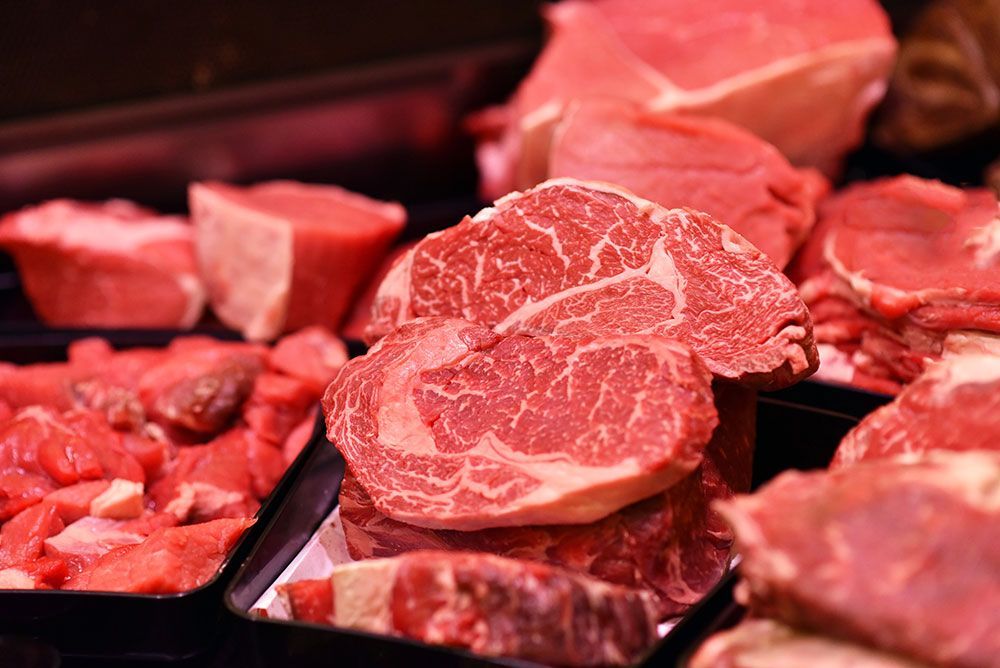 In einer Metzgerei werden rohe Stücke von rotem Fleisch ausgestellt, die die Marmorierung zur Schau stellen.