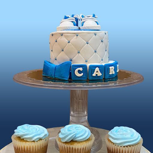 Un pastel y cupcakes en un soporte para pasteles con el nombre Carl en él.