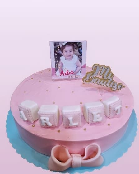 Un pastel rosa con la imagen de un bebé encima.