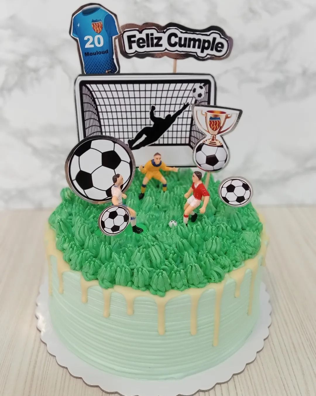 Una tarta de cumpleaños decorada con jugadores de fútbol y un gol.