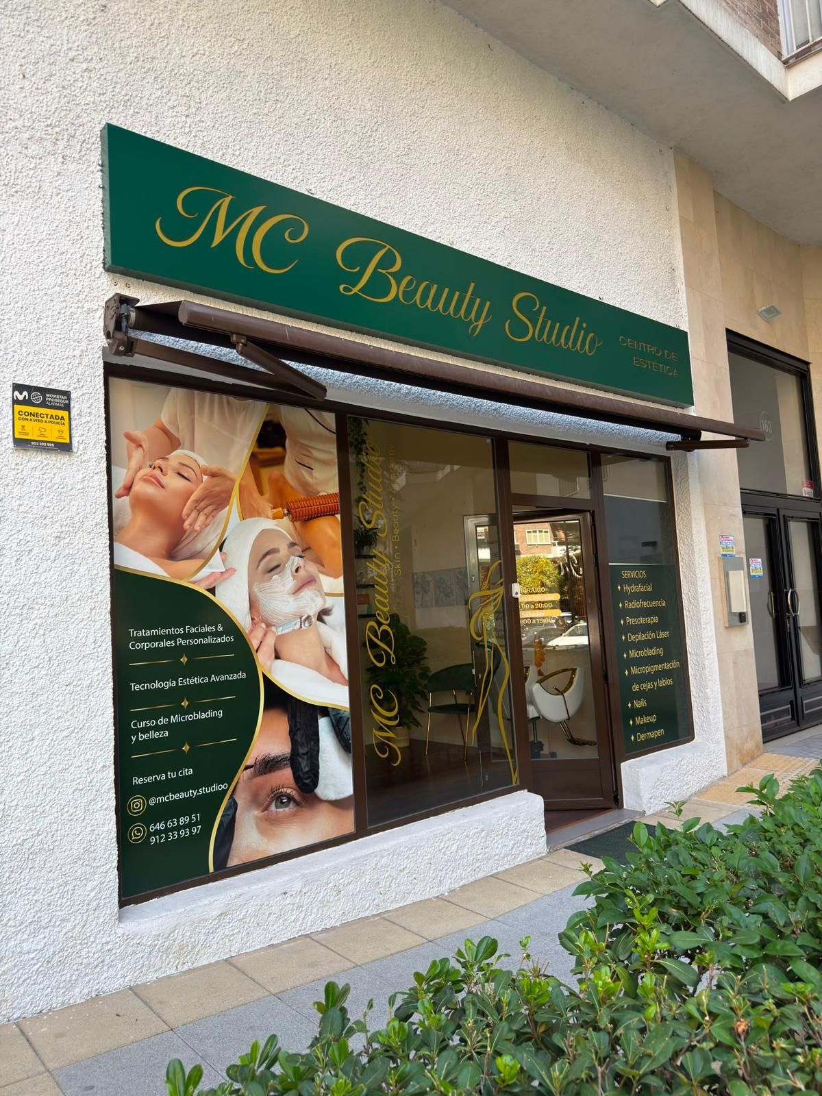 Fachada de “MC Beauty Suite” con toldo verde, puerta de cristal y carteles de tratamientos de belleza.