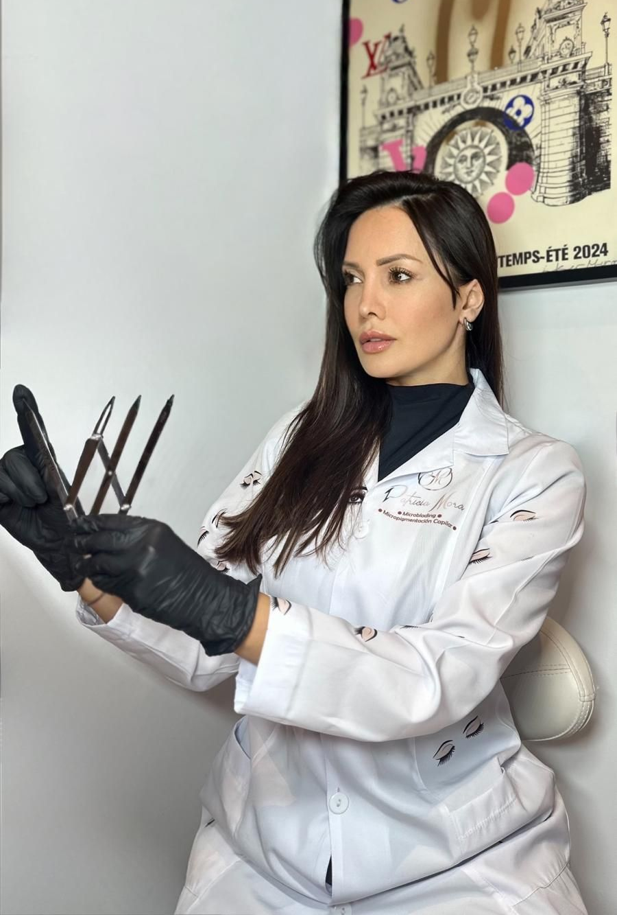 Persona con bata blanca y guantes negros sosteniendo unas tijeras en un salón de belleza, mirando hacia un lado.
