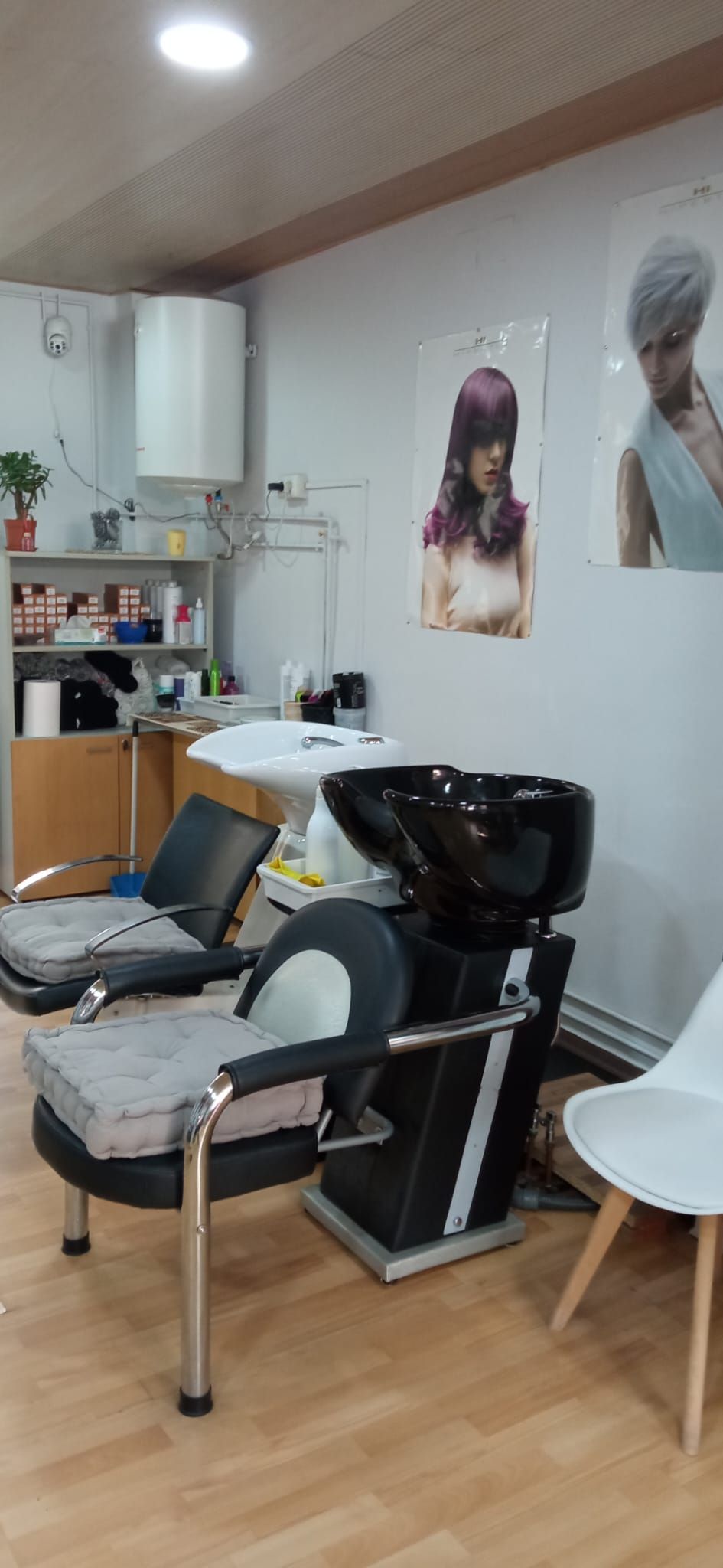 Una peluquería con lavabo, sillas y una foto de una mujer en la pared.