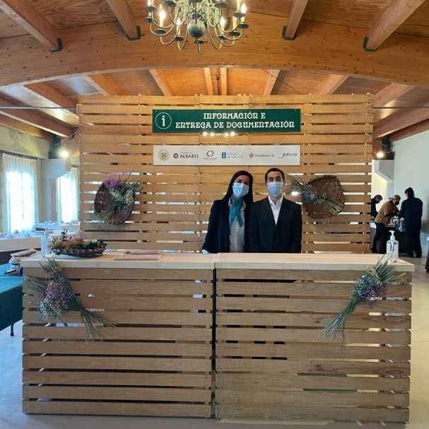 Dos personas con mascarillas se encuentran detrás de un mostrador de madera.