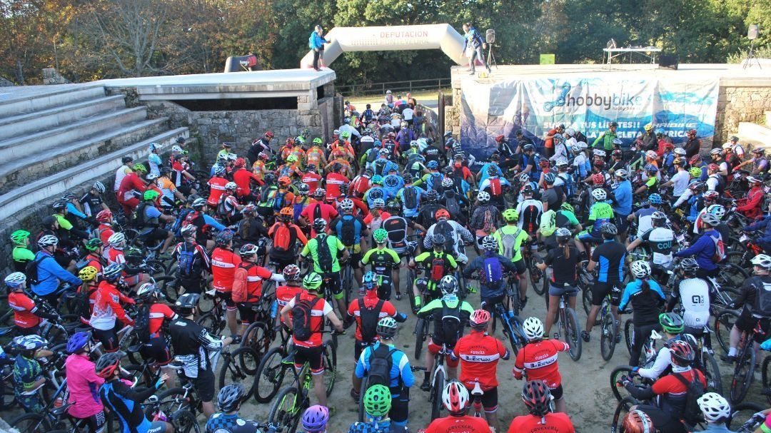 Un grupo grande de personas anda en bicicleta por un camino de tierra.