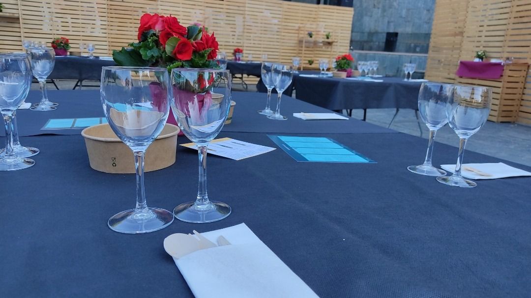 Una mesa con un jarrón de flores y copas de vino encima.