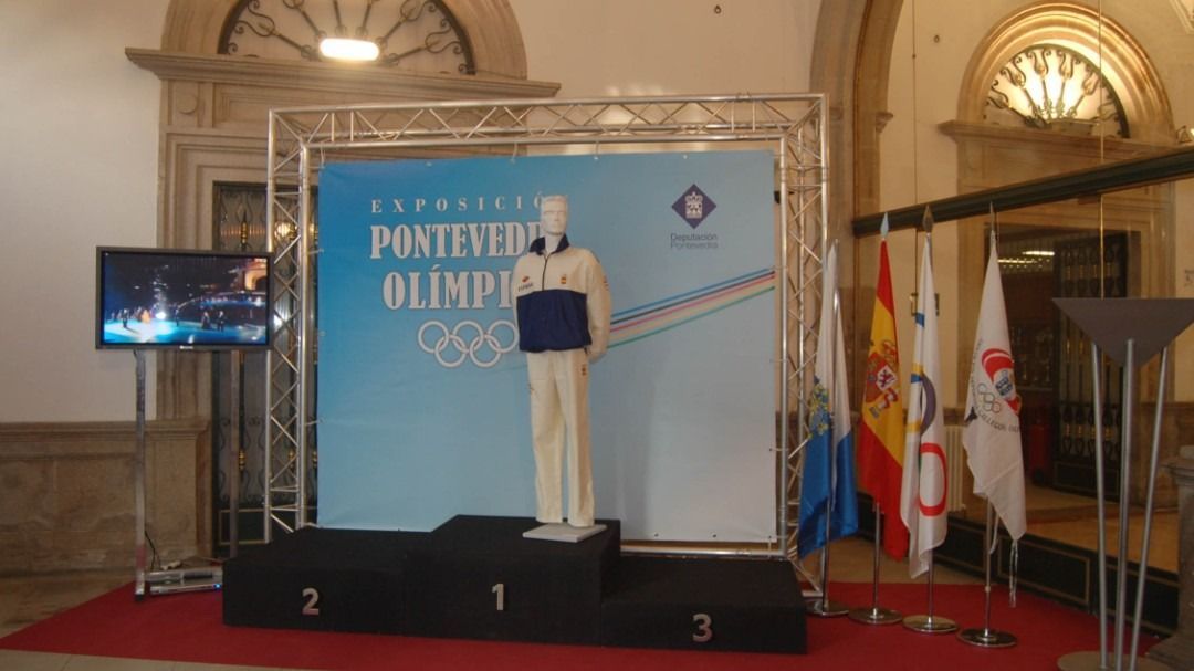 Un maniquí está de pie en un podio frente a un cartel que dice Juegos Olímpicos.