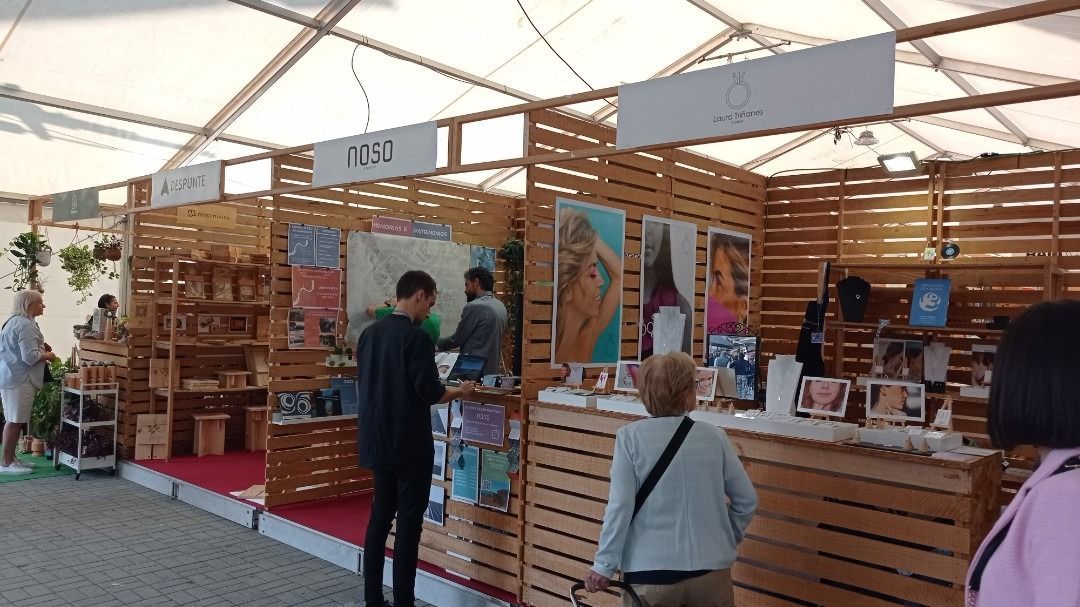 Un grupo de personas está de pie frente a una fila de puestos de madera.