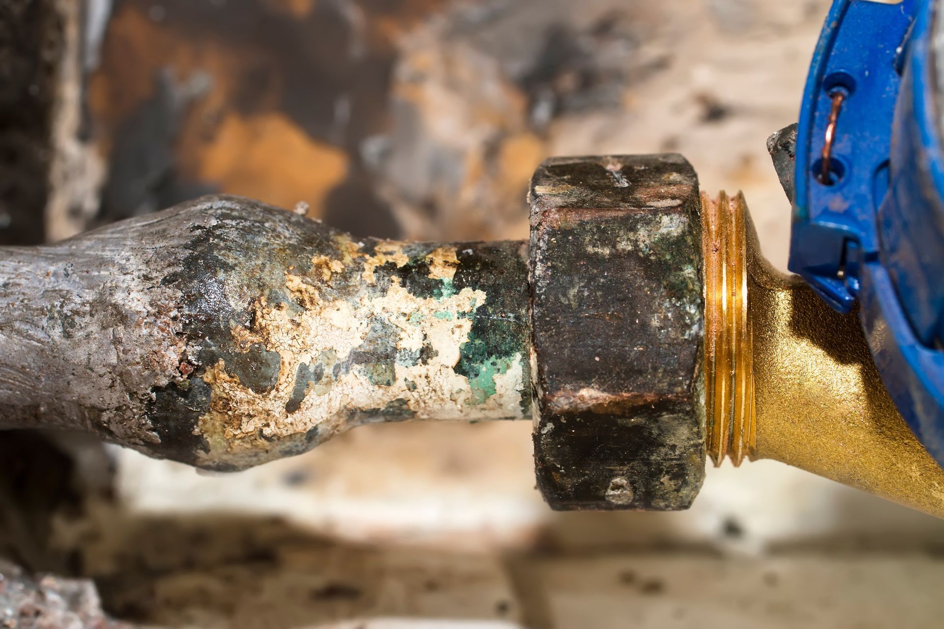 Raccord de tuyau corrodé avec un écrou rouillé et de la corrosion verte.