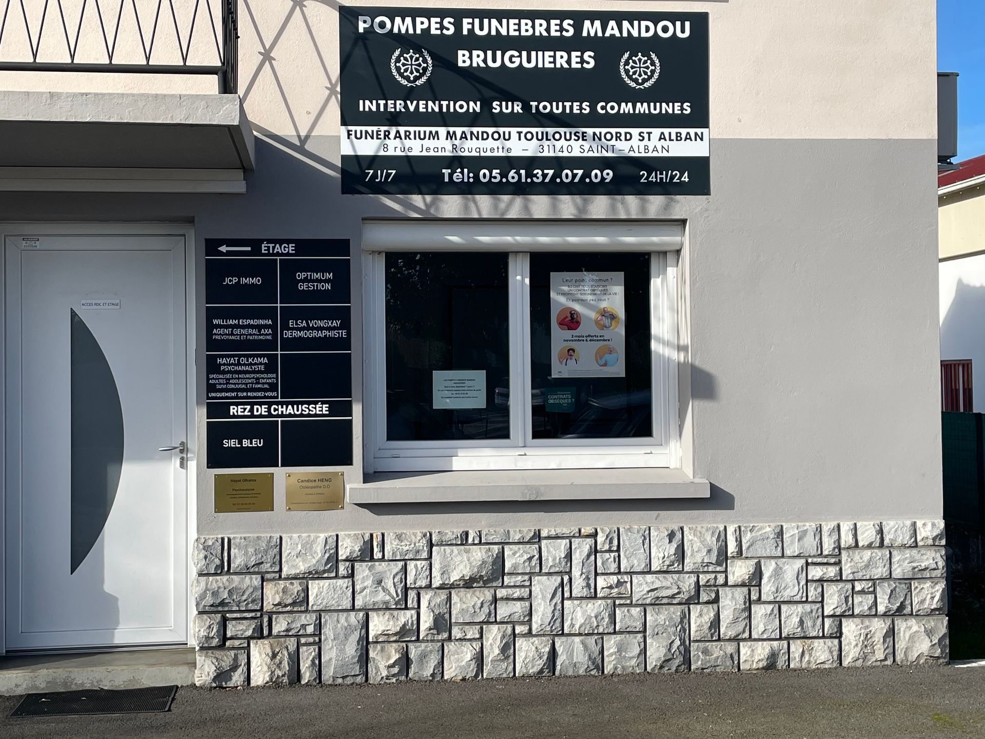 Une rangée de fourgonnettes argentées garées devant un bâtiment avec un emplacement de stationnement bleu réservé aux personnes handicapées.