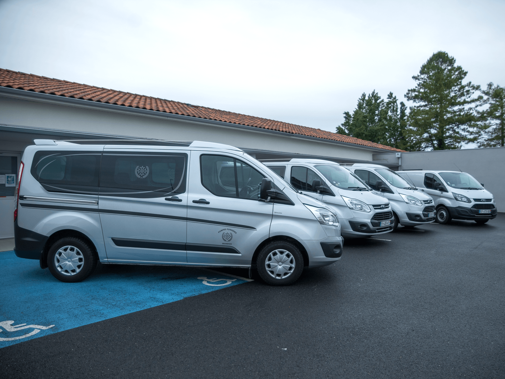 Une rangée de fourgonnettes argentées garées devant un bâtiment avec un emplacement de stationnement.