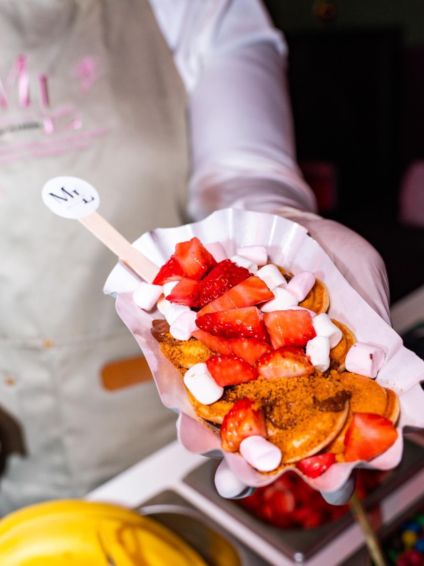 Une pile de petites crêpes dorées sur une assiette blanche, garnies de myrtilles fraîches, de framboises et de crème blanche.