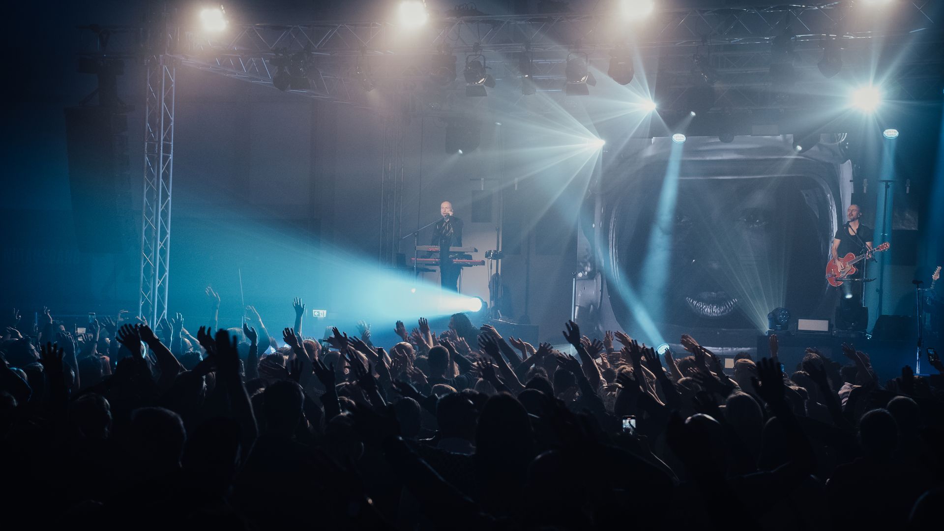 Bei einem Konzert steht eine Menschenmenge vor einer beleuchteten Bühne.