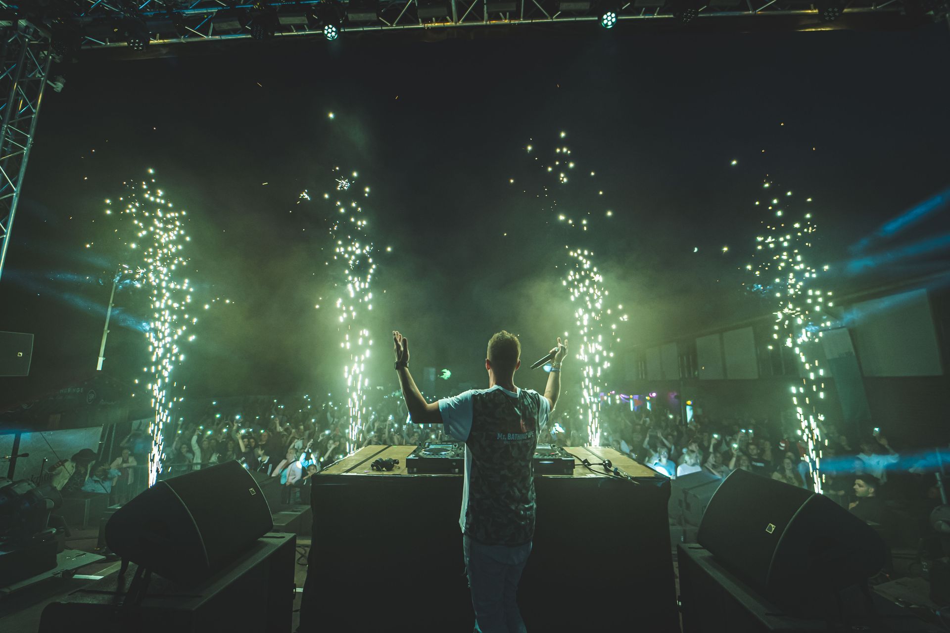 Ein Mann steht auf einer Bühne und hält ein Mikrofon vor einer Menschenmenge.