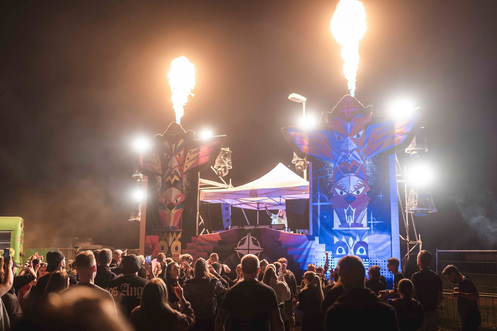 Nachts findet ein Open-Air-Musikfestival mit Bühne, Pyrotechnik und Zuschauern statt.
