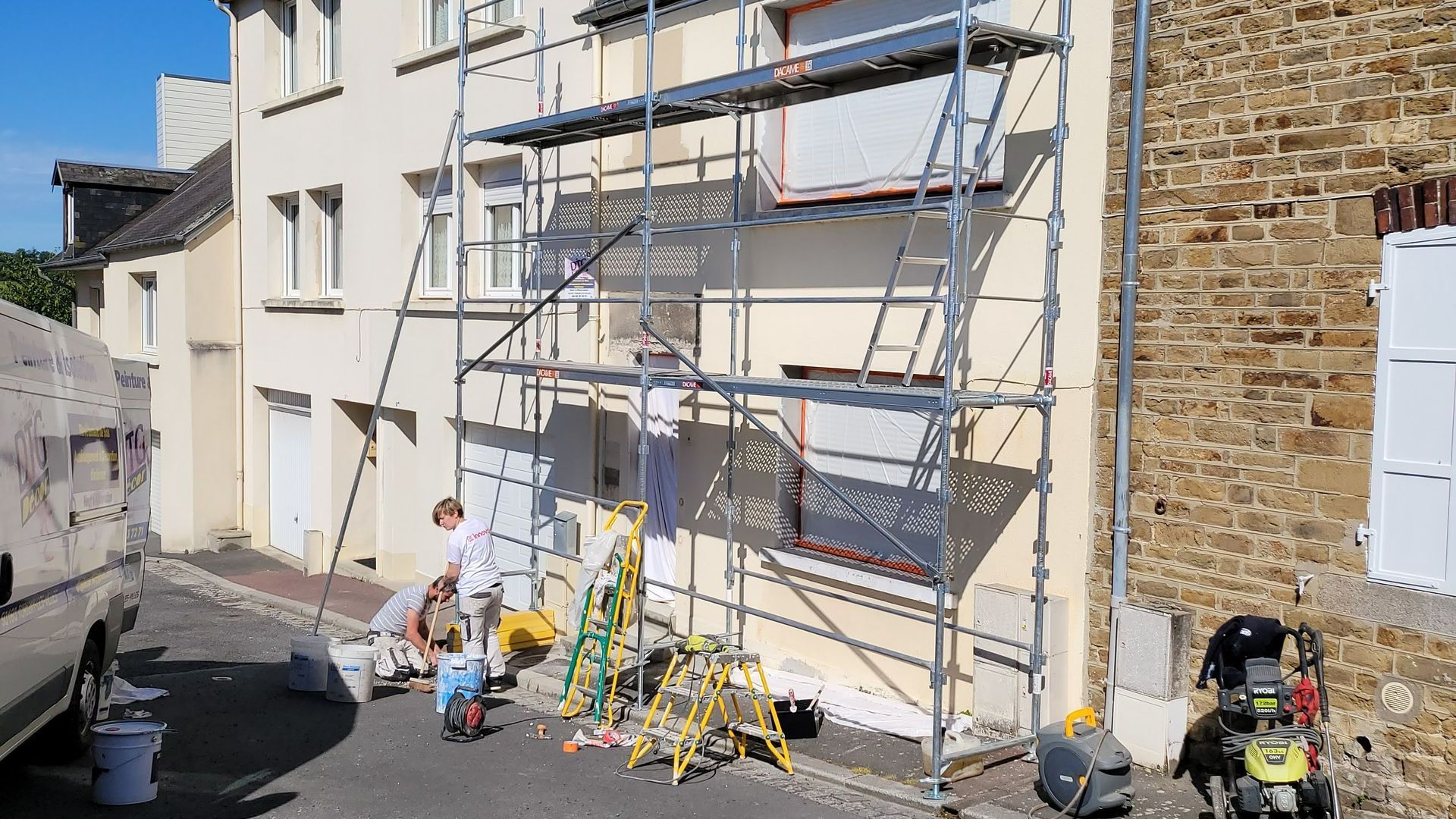 Deux artisans rénovent la façade d'une petite maison de ville.