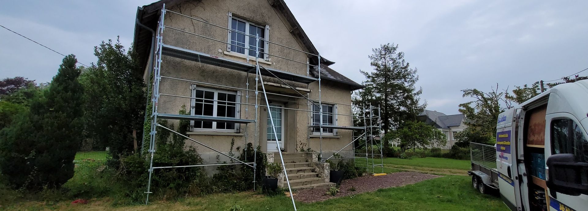 Une maison entourée d'un jardin en cours de ravalement.