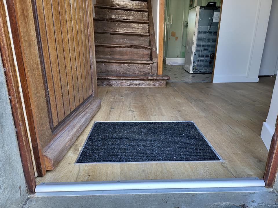 Entrée d'une maison avec porte ouverte sur sol en PVC.