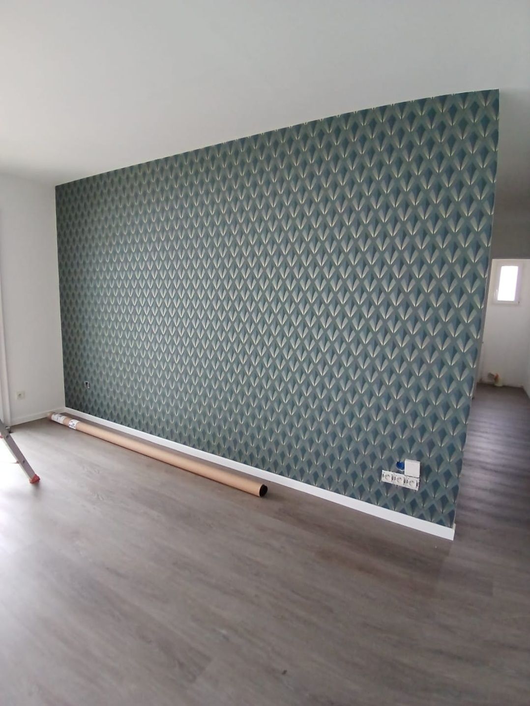 Pan de mur recouvert d'un papier peint blanc à motifs.