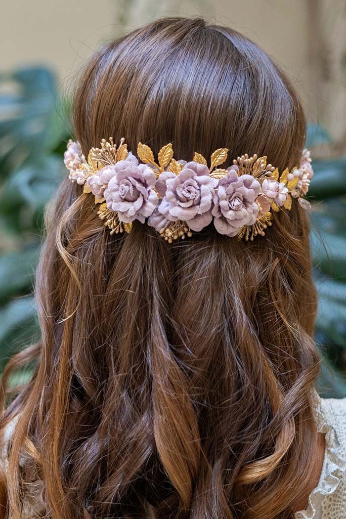 Vista posterior de cabello castaño ondulado con un adorno floral rosa pálido.