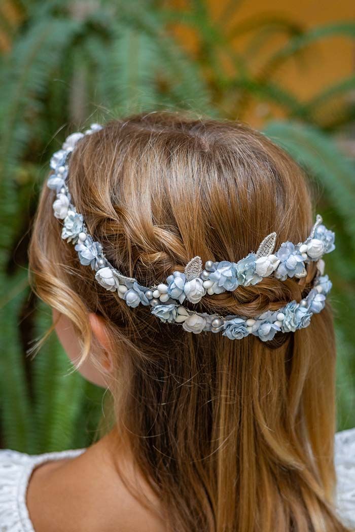 Parte posterior de la cabeza de una mujer con el cabello trenzado y adornado con un tocado floral blanco.