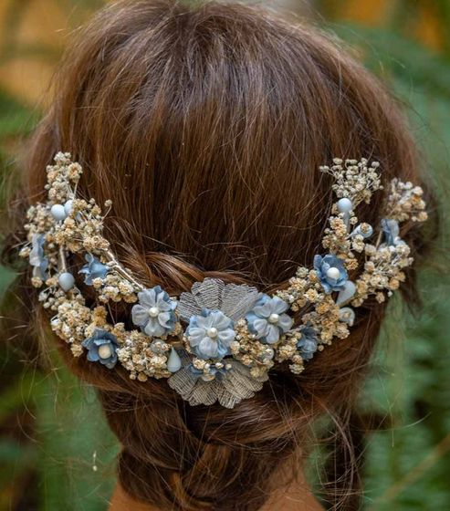 Primer plano de un moño de cabello castaño adornado con accesorios florales azules y blancos.