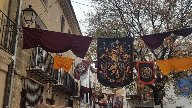 Un montón de banderas cuelgan de un mástil frente a un edificio.