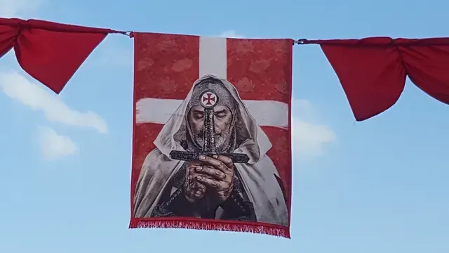 Una bandera roja y blanca con la imagen de un hombre sosteniendo una cruz