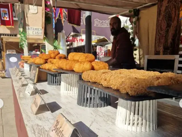 Un hombre parado detrás de un mostrador vendiendo comida frita.