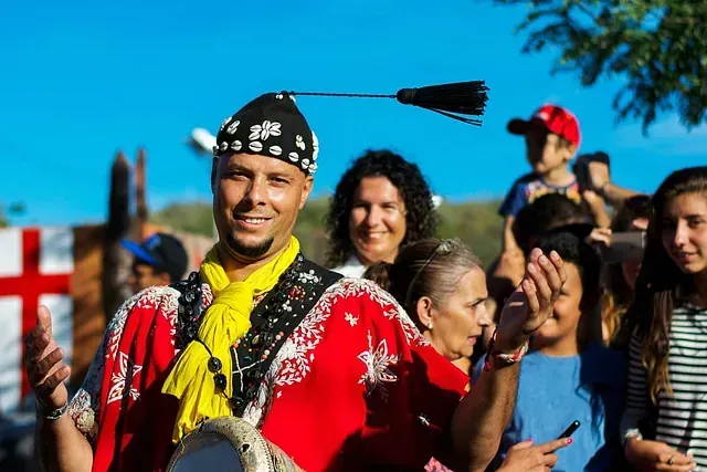 Un hombre vestido de rojo y amarillo está parado frente a una multitud de personas.