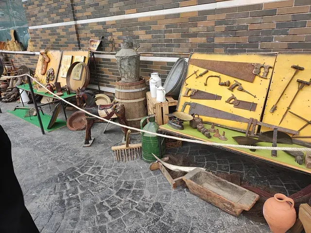 Una exposición de herramientas y utensilios antiguos frente a una pared de ladrillos.