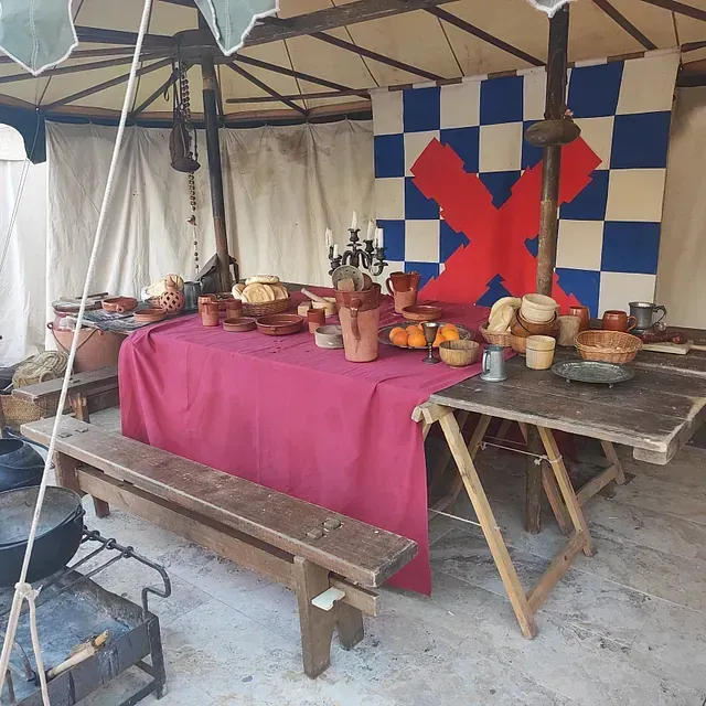 Una mesa con un mantel rojo y una pared a cuadros detrás.
