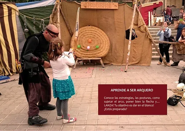 Un hombre y una niña están jugando al tiro con arco frente a un objetivo.